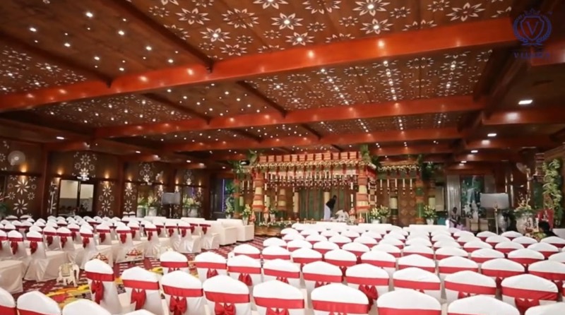 Aura hall mandap beneath a carved wooden ceiling