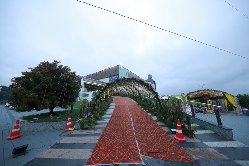 Red carpet walkway under floral arches leading to the venue