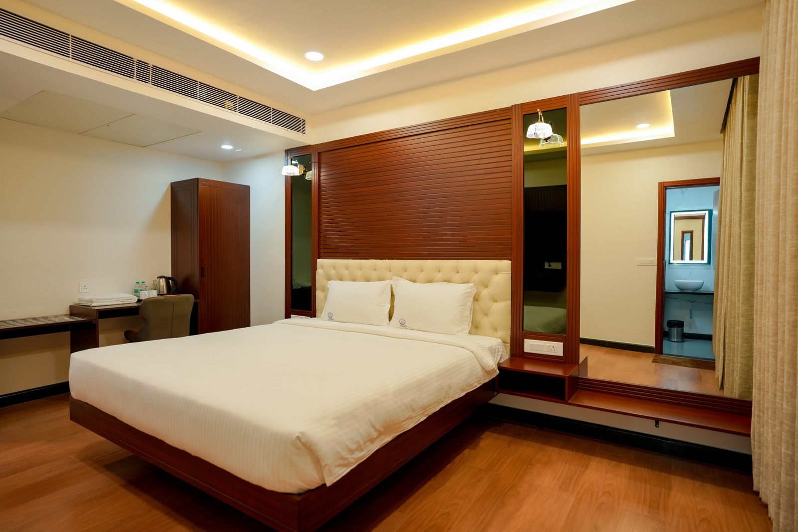 Deluxe room with a king bed, tufted headboard and warm wooden panelling
